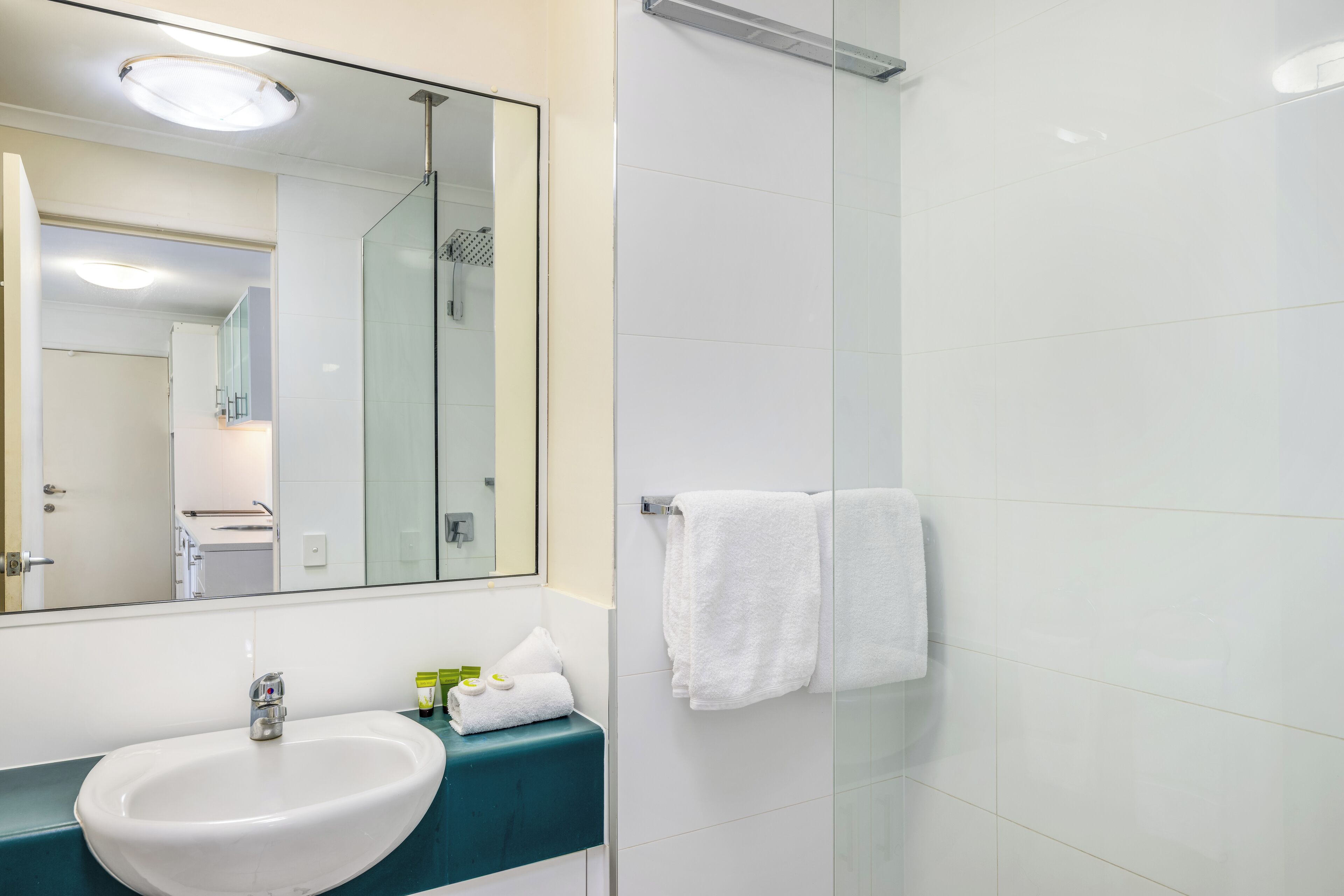 A bathroom with a white sink, a mirror, and a glass shower enclosure.
