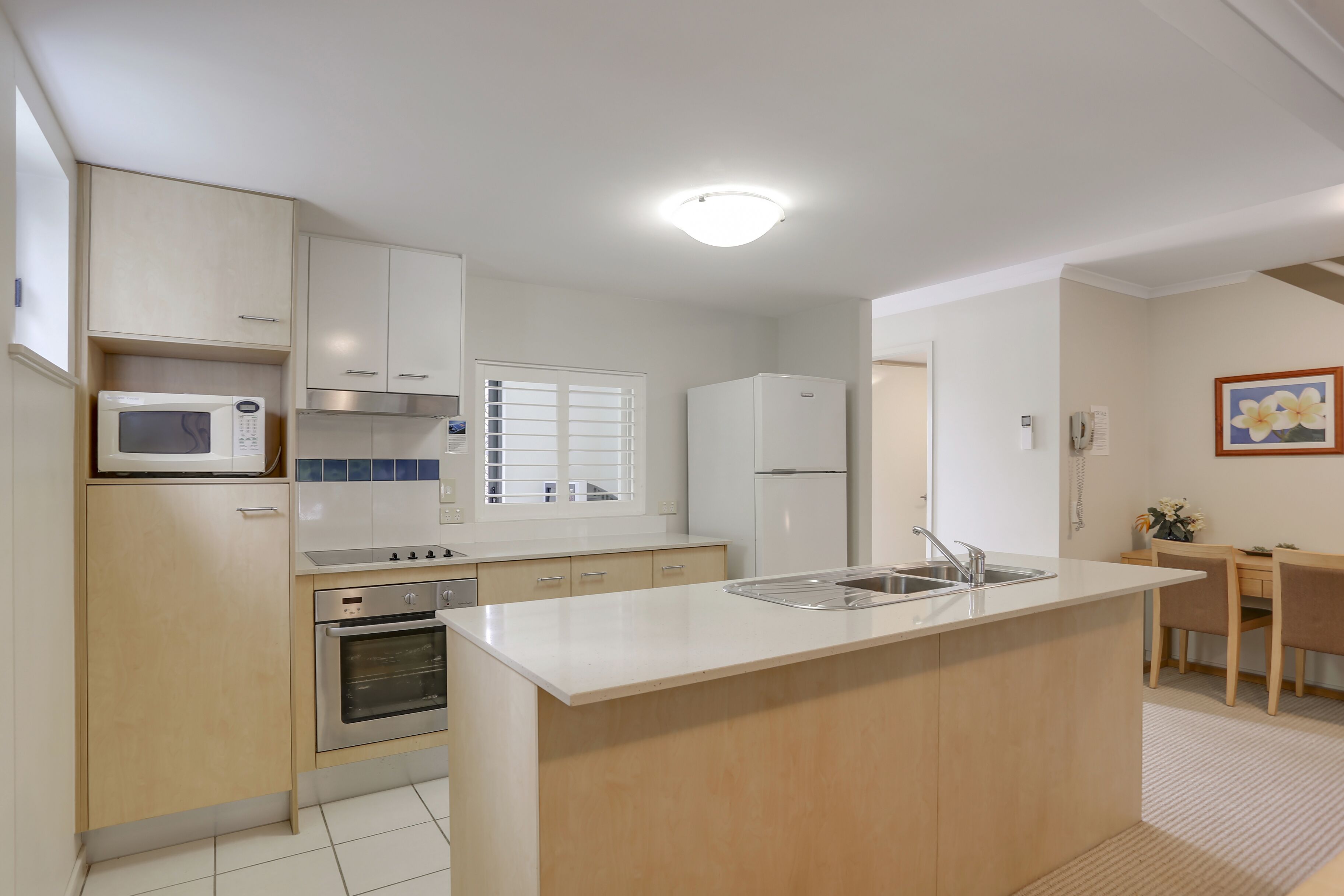 A modern kitchen with white cabinets, stainless steel appliances, and a central island with a sink.