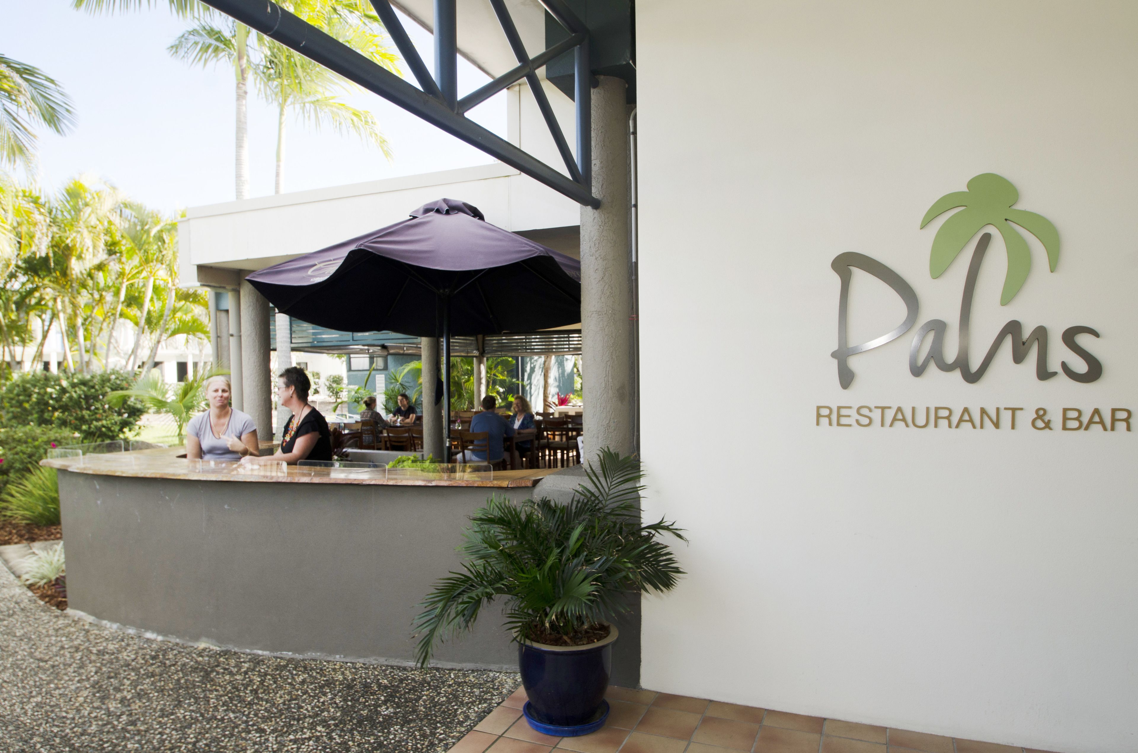 Een terras met een palmboom en een bordje voor 