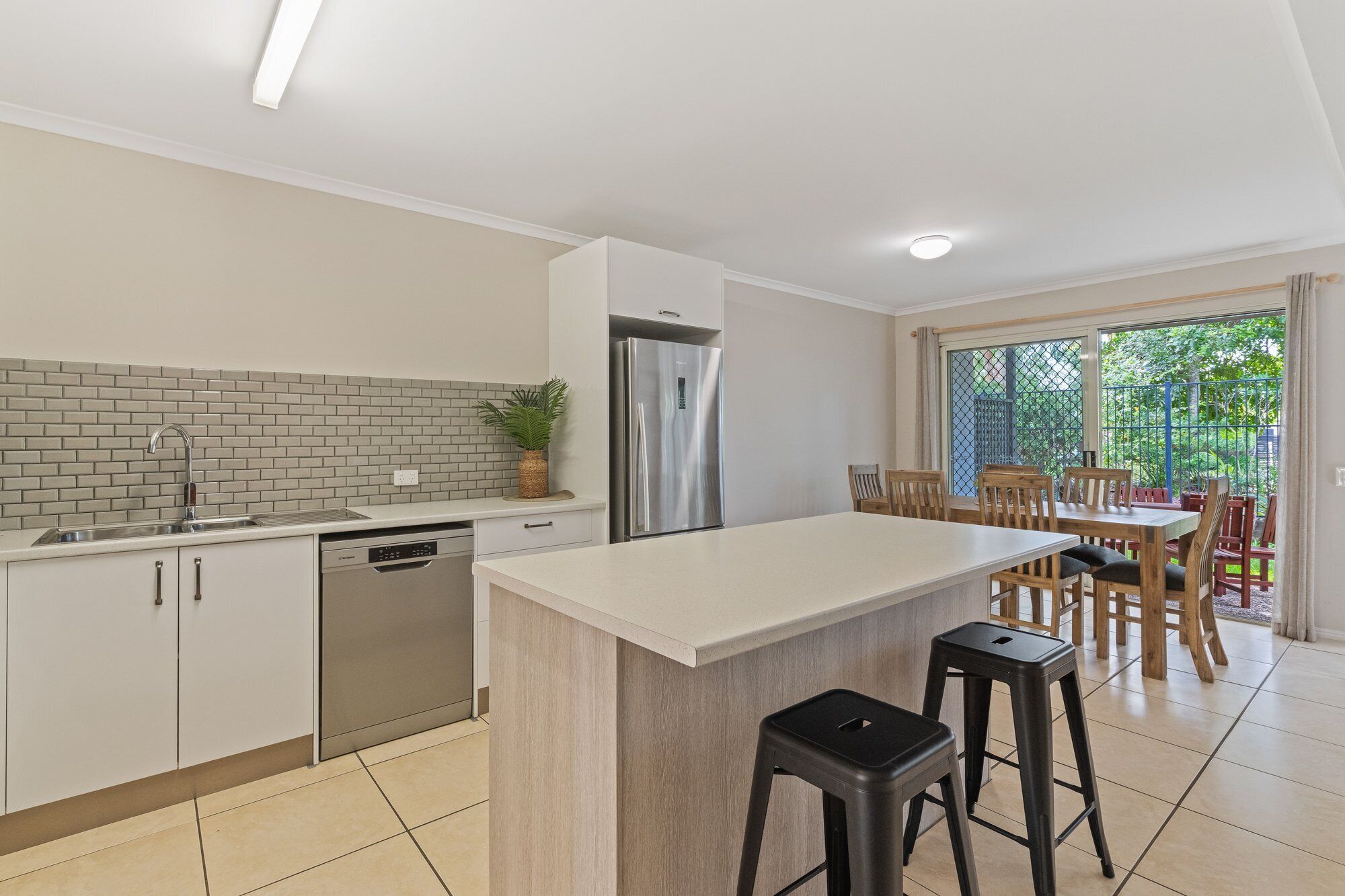 A modern kitchen with a central island, stainless steel appliances, and a dining area with wooden furniture.