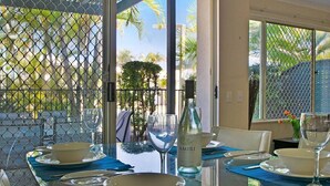 Comedor con mesa de vidrio, sillas y una botella de Amiri.