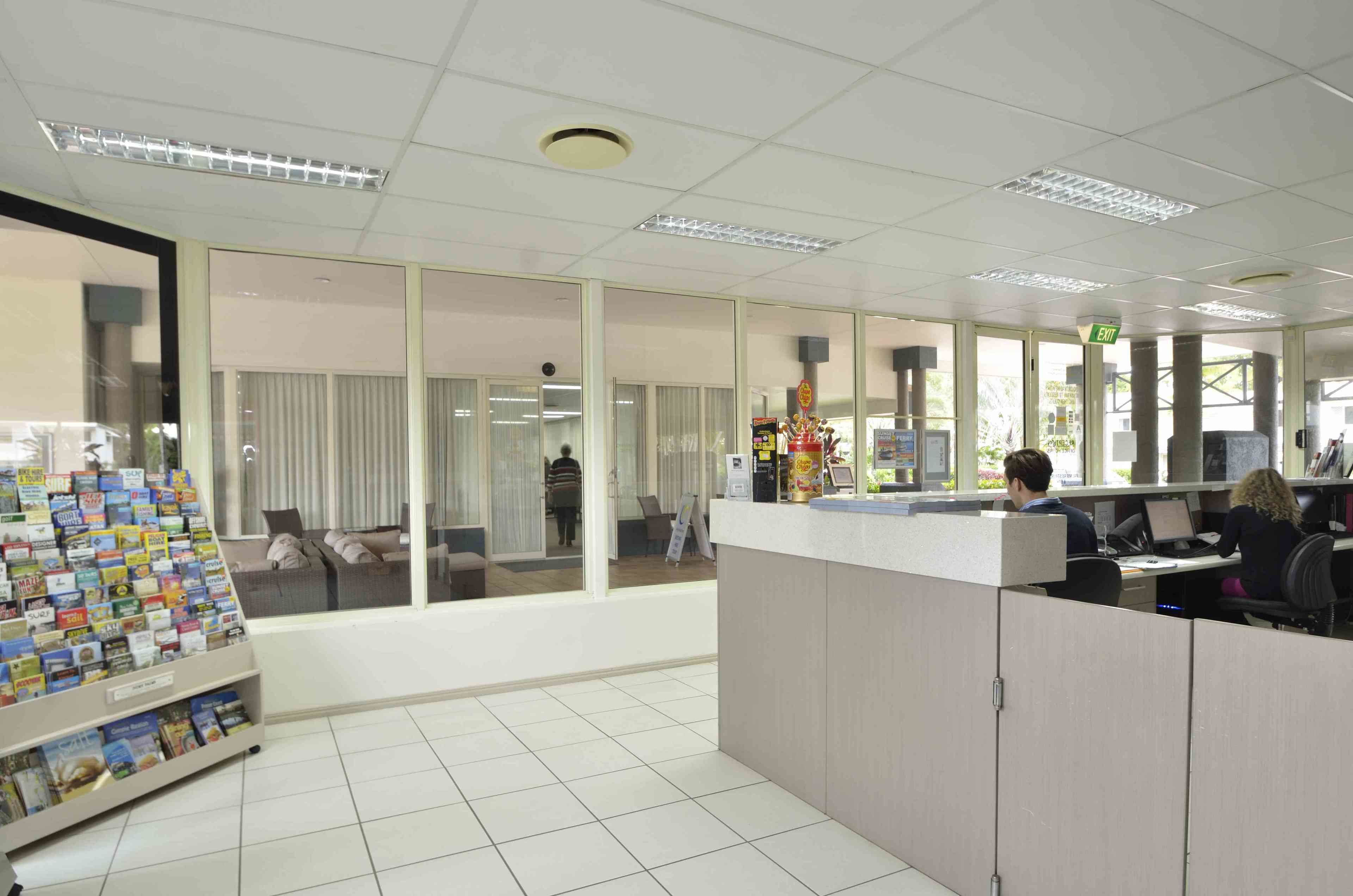 A modern office space with glass partitions, a reception area, and a display of promotional materials.