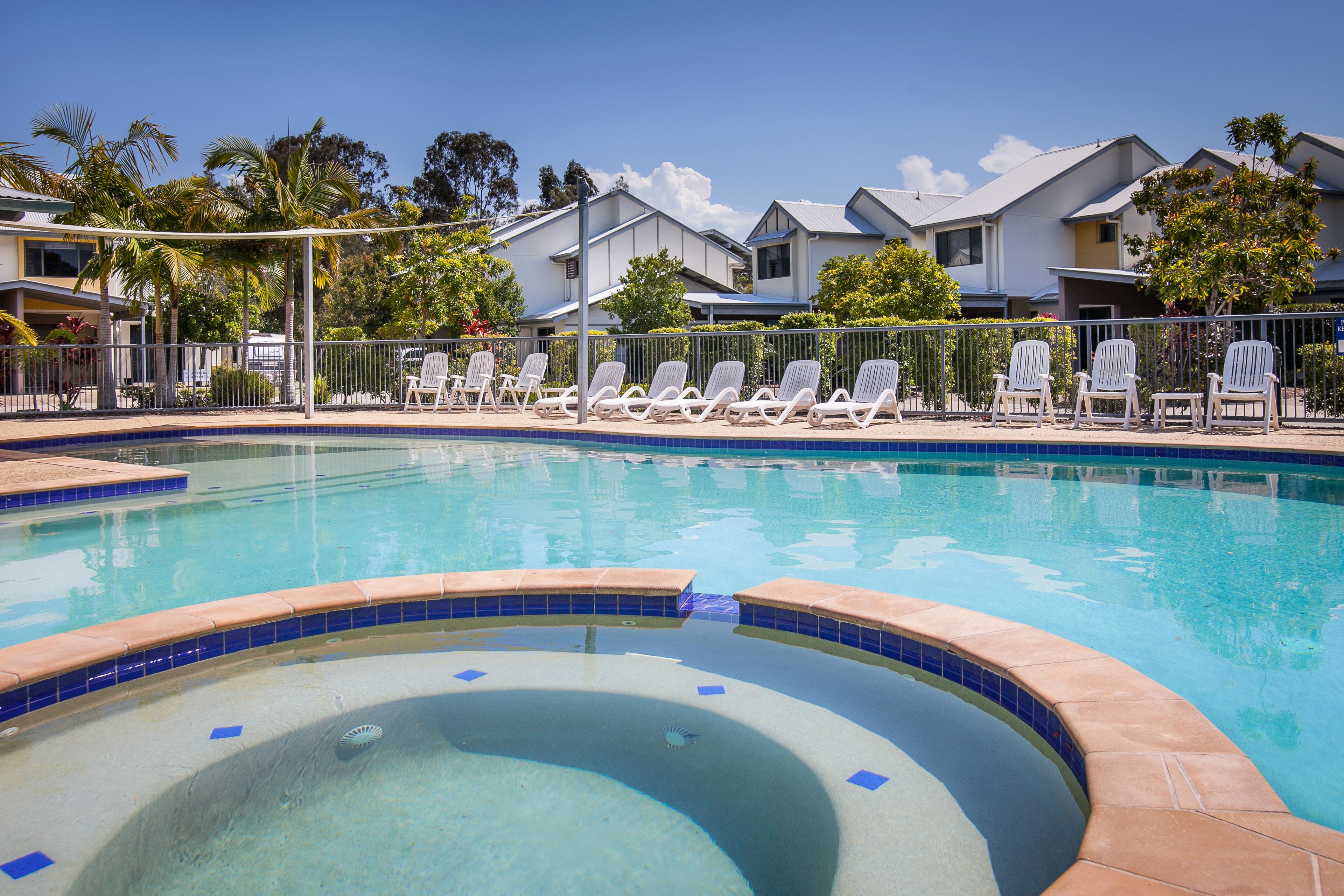 A swimming pool with lounge chairs and a tiled deck.