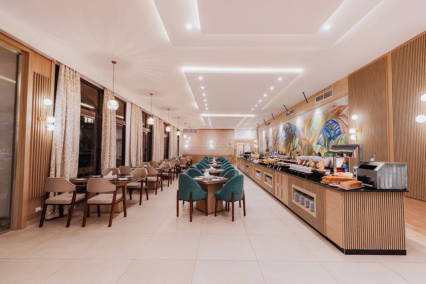 Un restaurante moderno con una barra larga, varias zonas de estar y un mural decorativo en la pared.