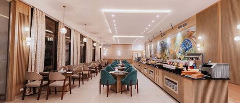 Un restaurante moderno con una barra larga, varias zonas de estar y un mural decorativo en la pared.