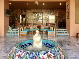 Un vestíbulo con una fuente de mosaicos, zona de estar y una escalera.
