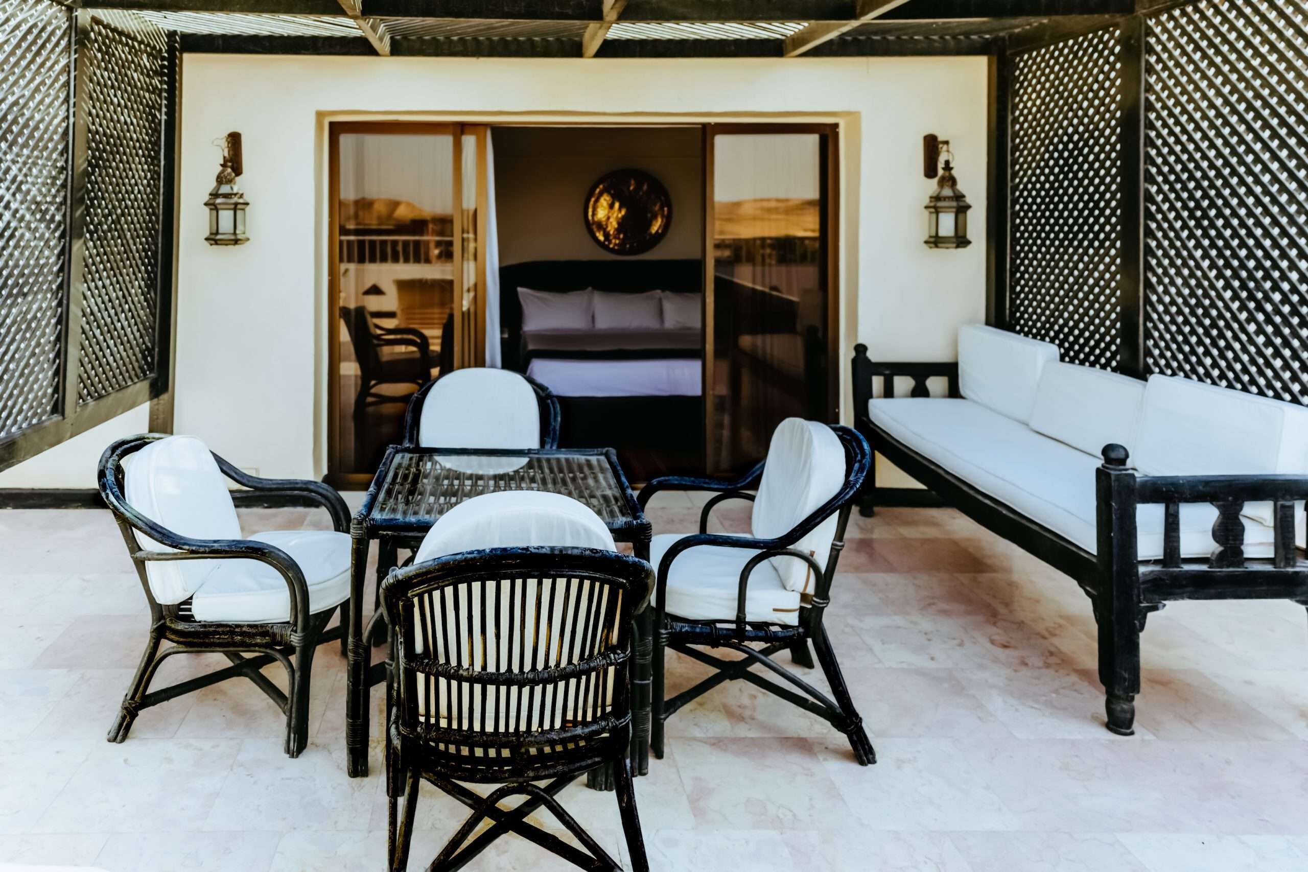 An outdoor patio with a dining table and chairs, a sofa, and a bed with a view.