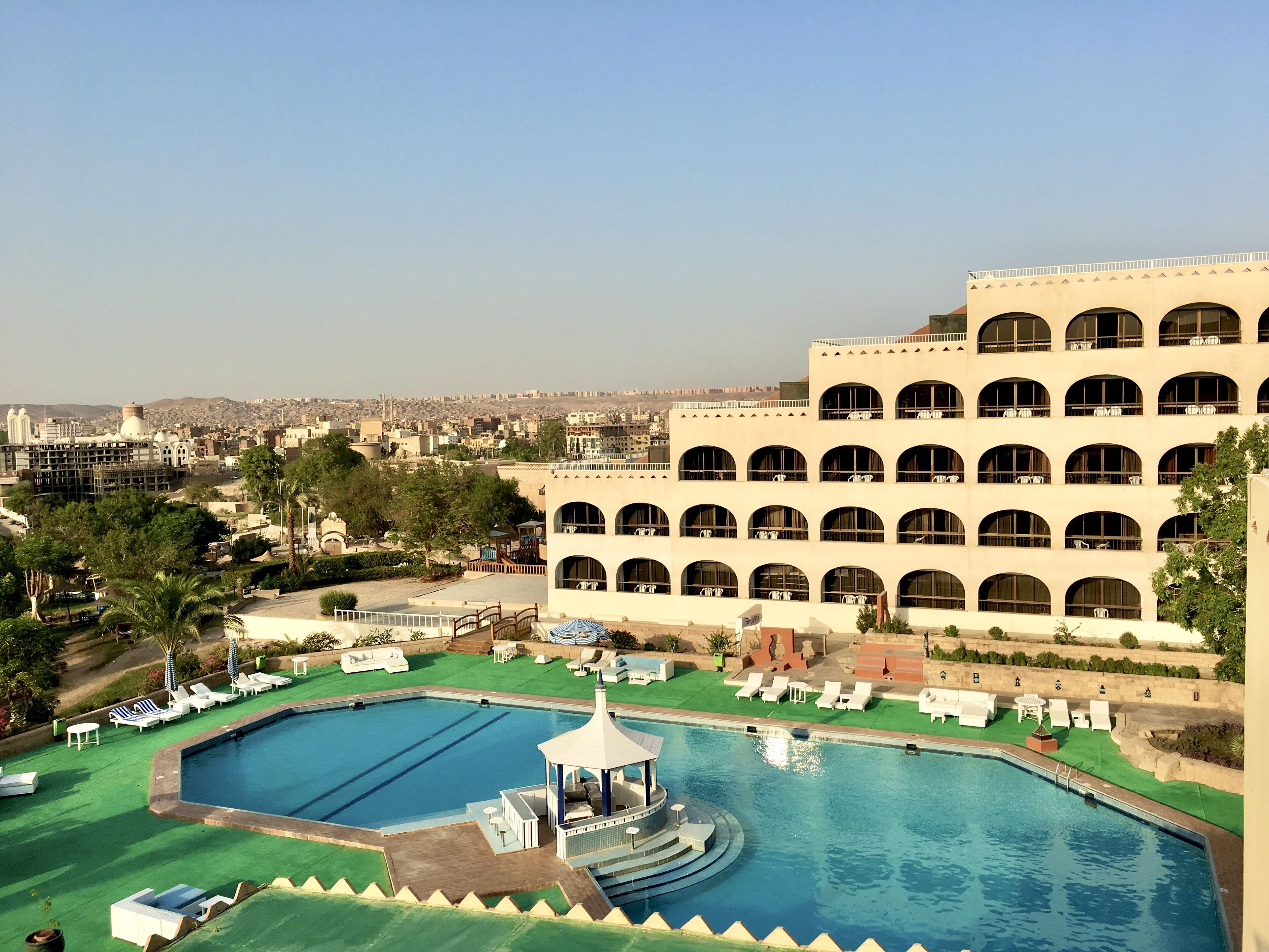 Un hotel con piscina, sillas de descanso y un pabellón.
