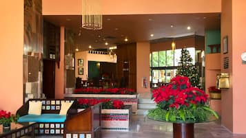 Un vestíbulo con zona de estar, un árbol de Navidad y una recepción.