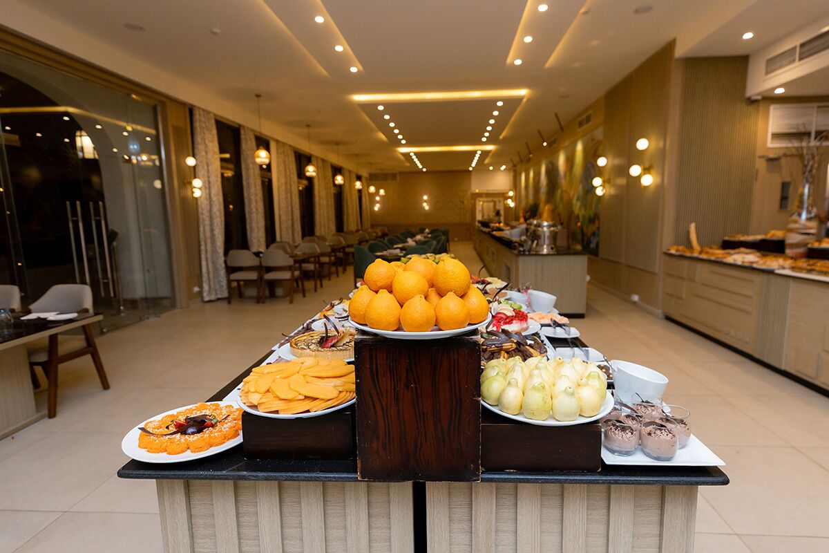 A buffet setup in a hotel dining area with various food items and a long table.