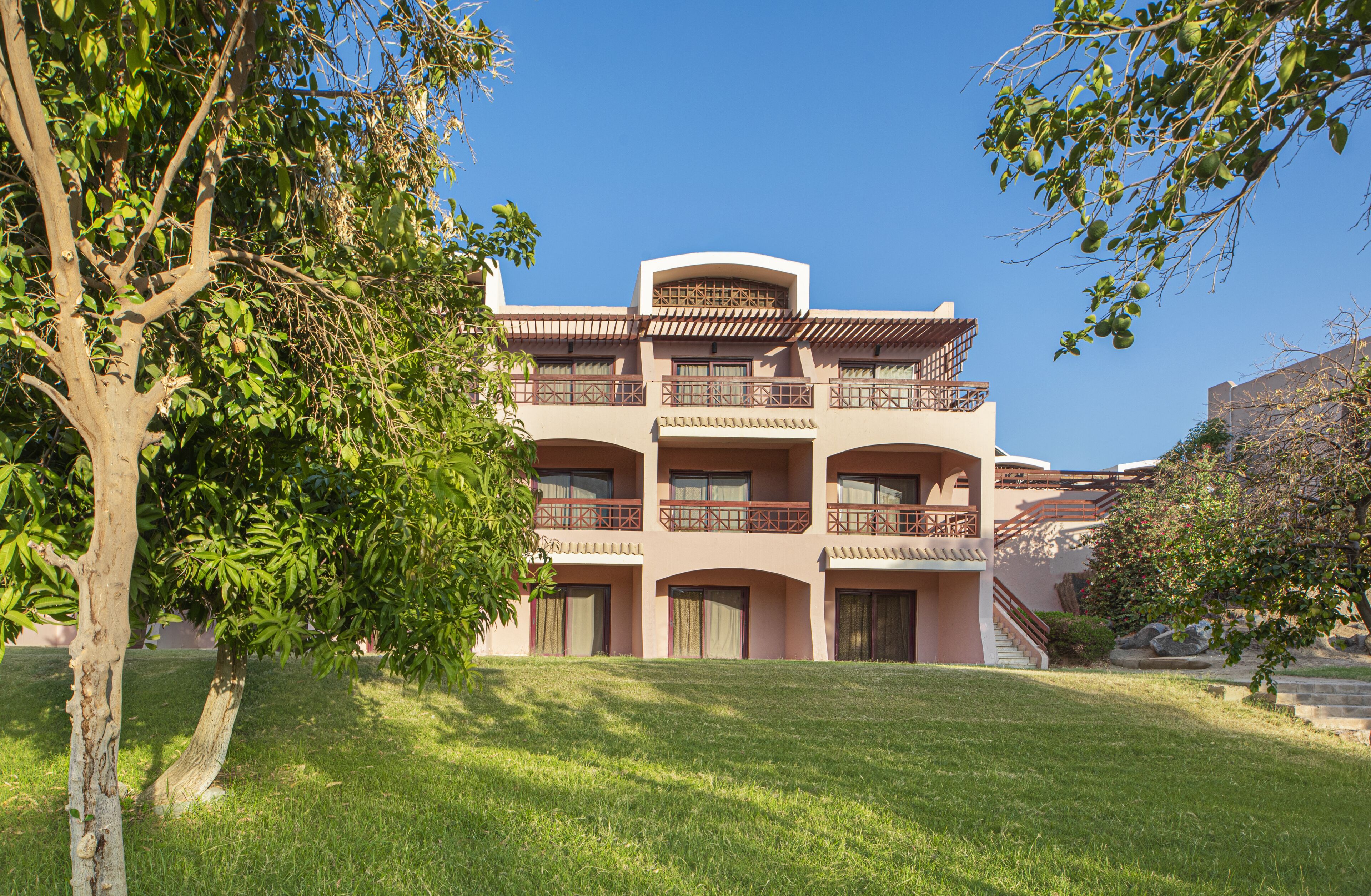 A multi-story building with balconies and a staircase leading to the entrance.