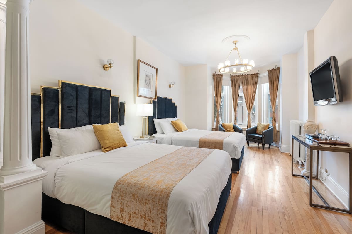 Ein Hotelzimmer mit zwei Betten, einem Fernseher, einem Schreibtisch und einem Sessel.