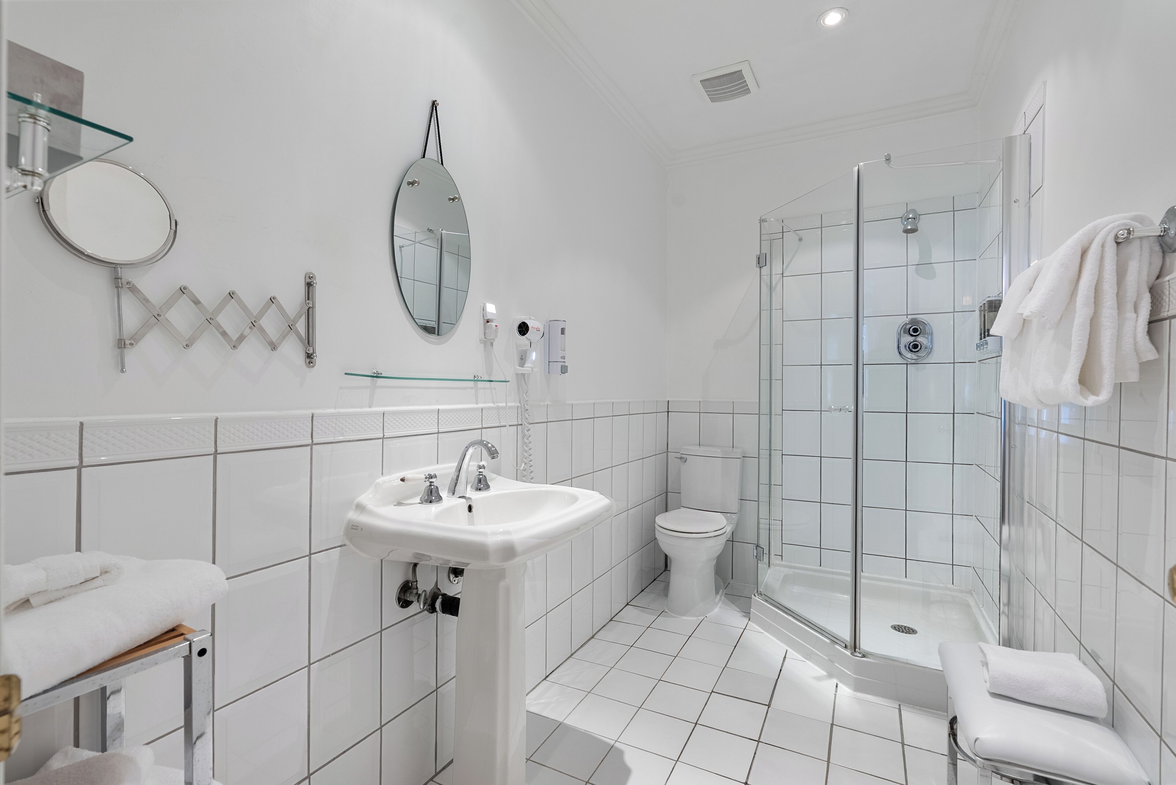 A modern bathroom with a glass shower enclosure, a toilet, and a sink with a mirror above it.