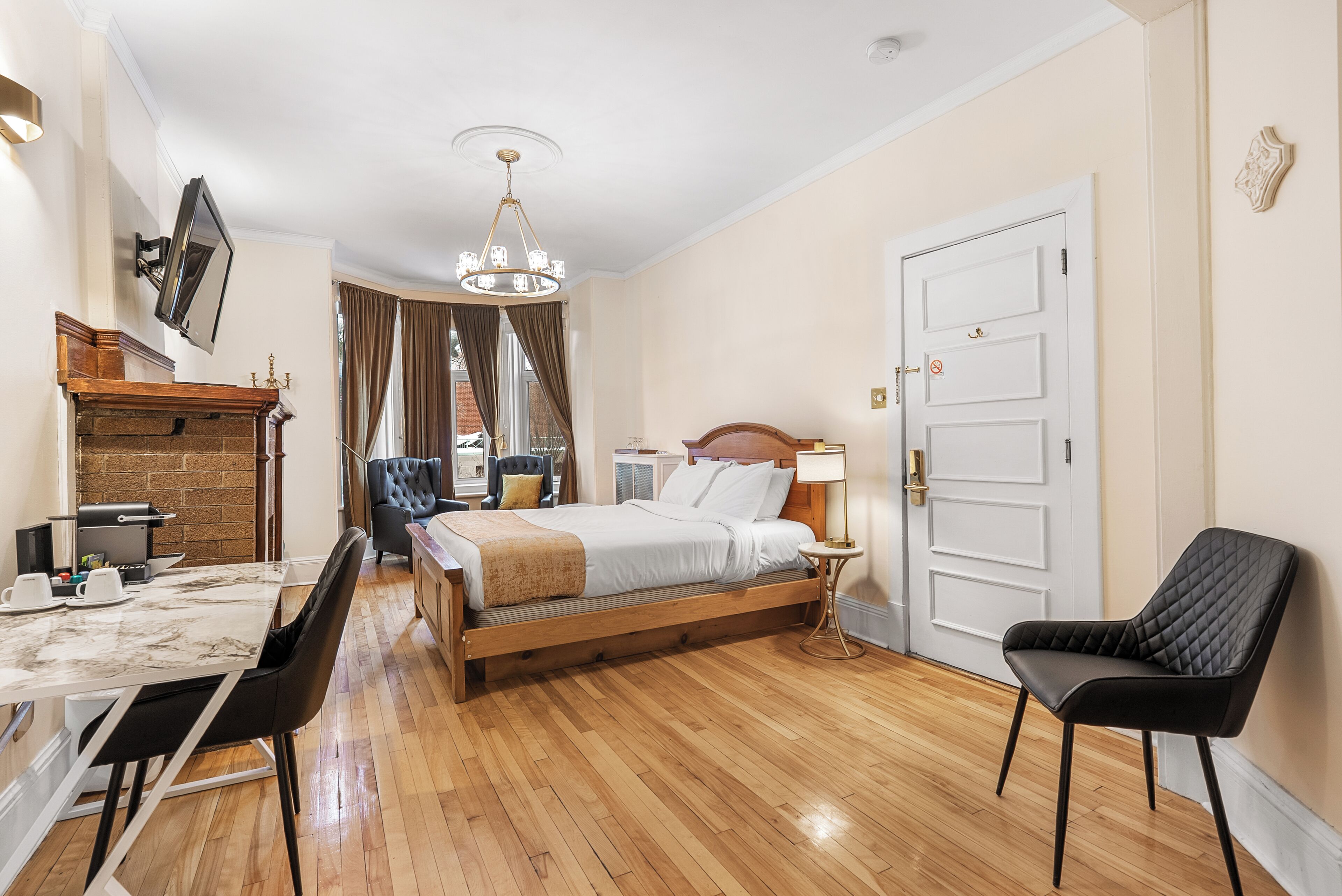 Un dormitorio con cama de madera, una mesa de comedor con sillas, un televisor montado en la pared y una araña.