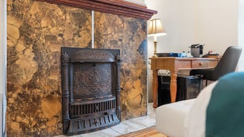Una habitación con chimenea, un escritorio, una silla y una lámpara.