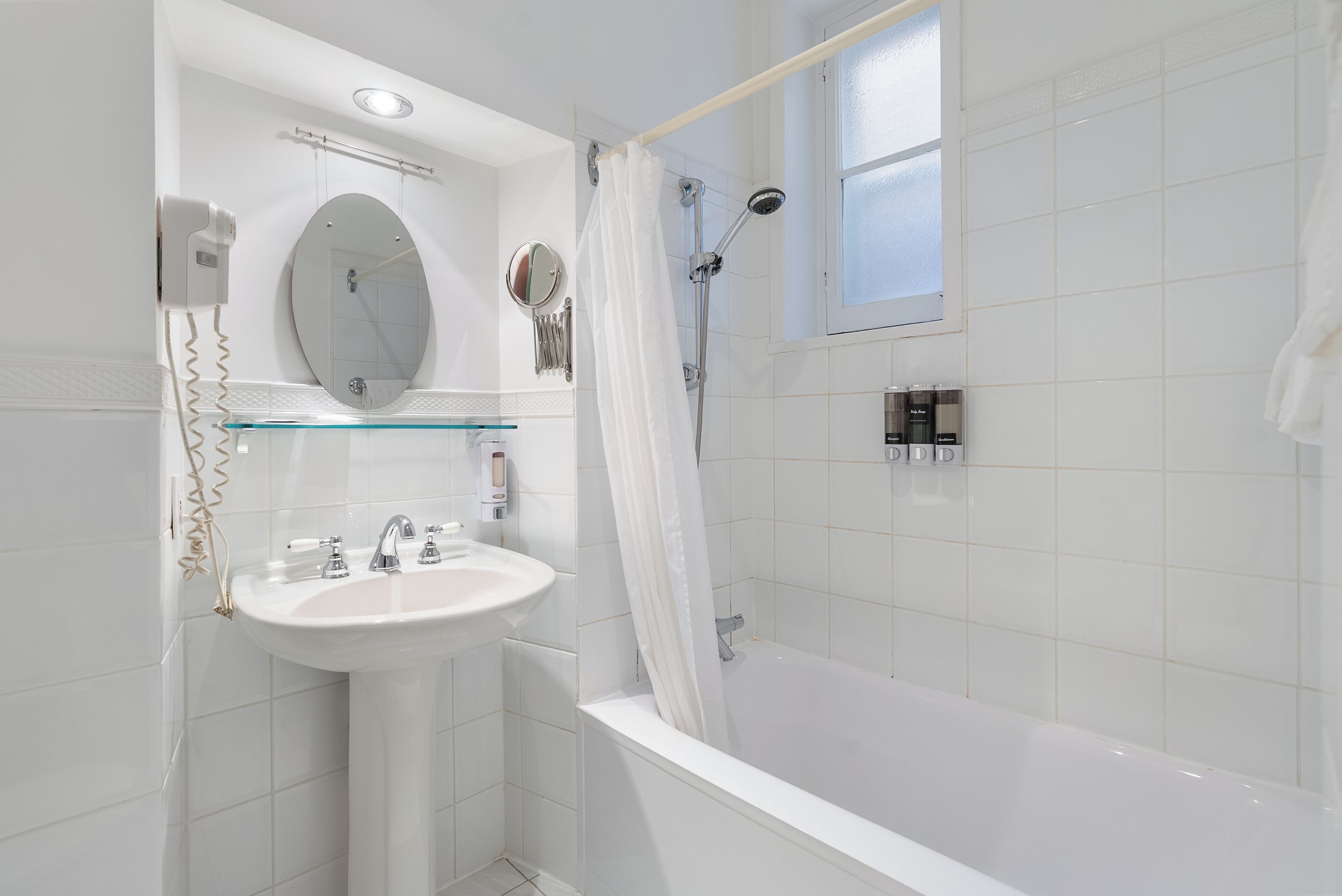 Un baño moderno con lavamanos, espejo y ducha blancos.