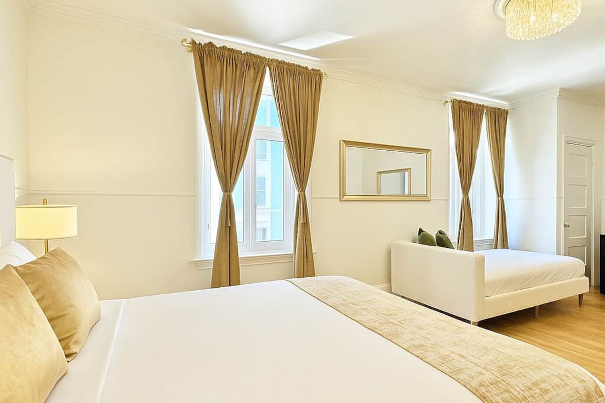 Ein Hotelzimmer mit einem großen Bett, einer Couch, einer Chandelier und einem Spiegel an der Wand.