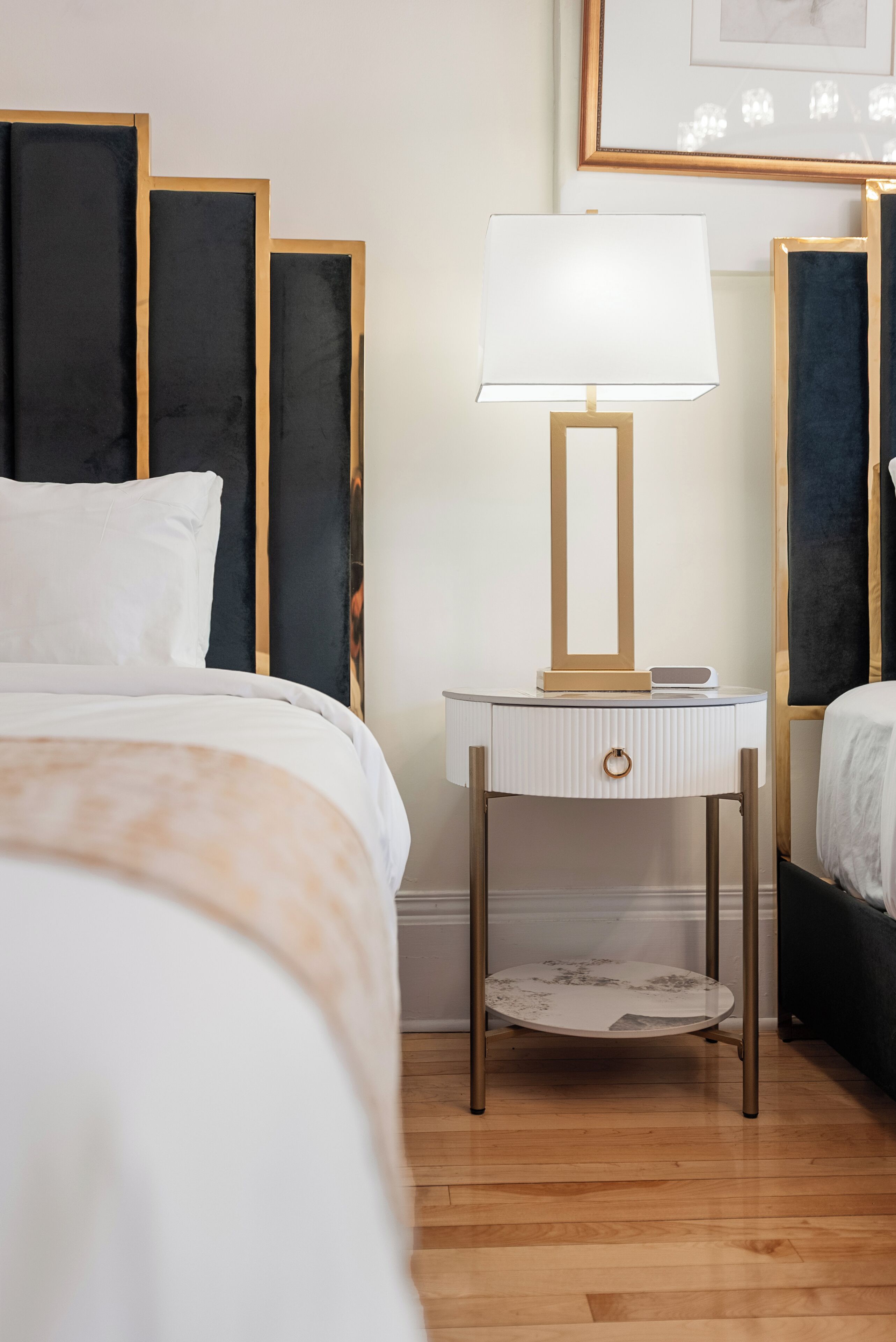 A neatly arranged hotel room with a bed, bedside table with a lamp, and a framed picture on the wall.