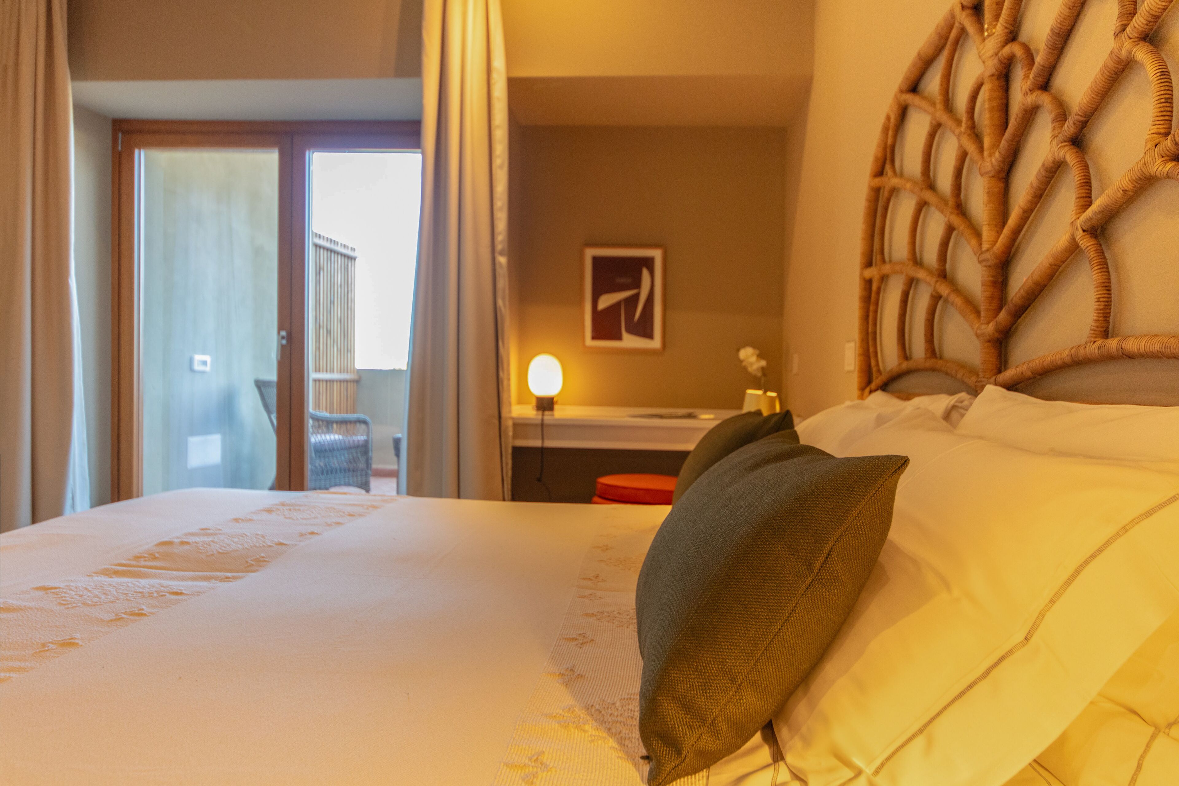 A hotel room with a bed, a desk, a chair, and a view of the outside.