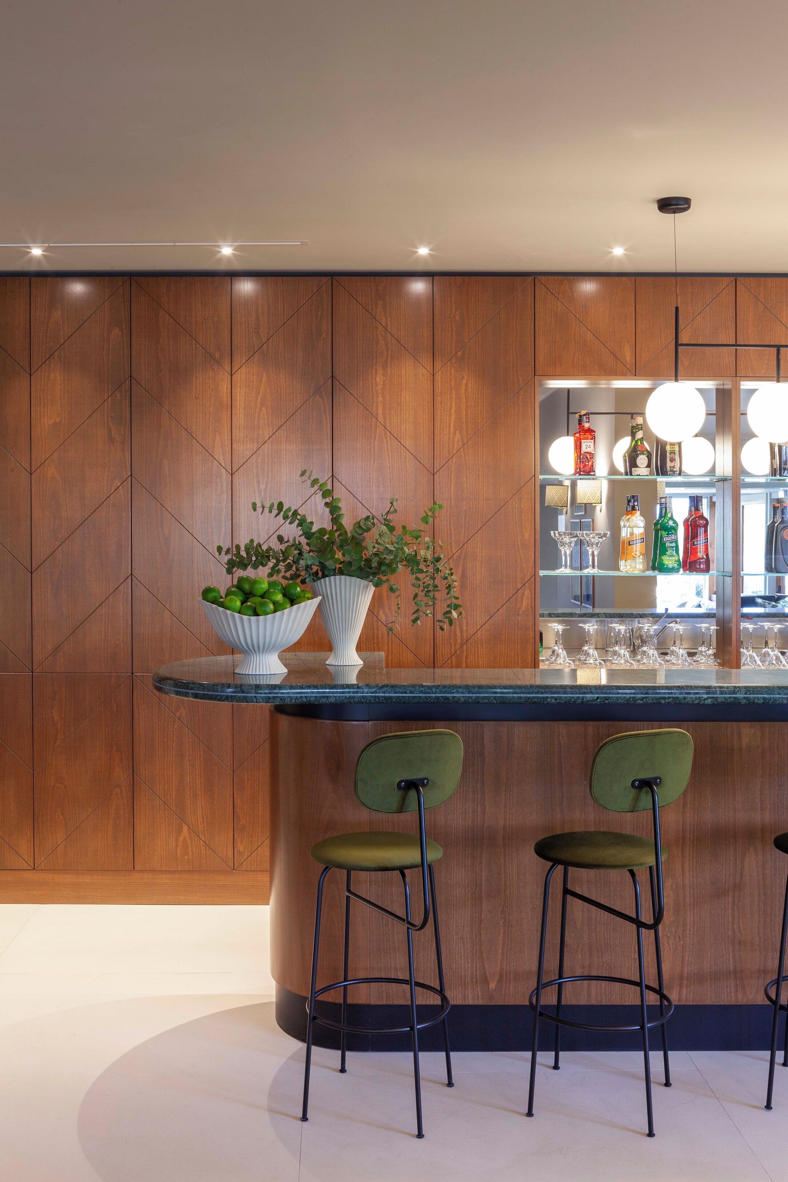 A modern kitchen with wooden cabinetry, a bar area with stools, and a countertop with a potted plant.