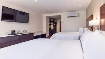 Habitación de hotel con dos camas, televisión de pantalla plana, escritorio con hervidor y armario.