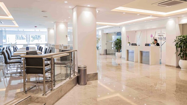 Un hall d’hôtel comprenant un comptoir d’accueil, un espace salon et de grandes fenêtres.