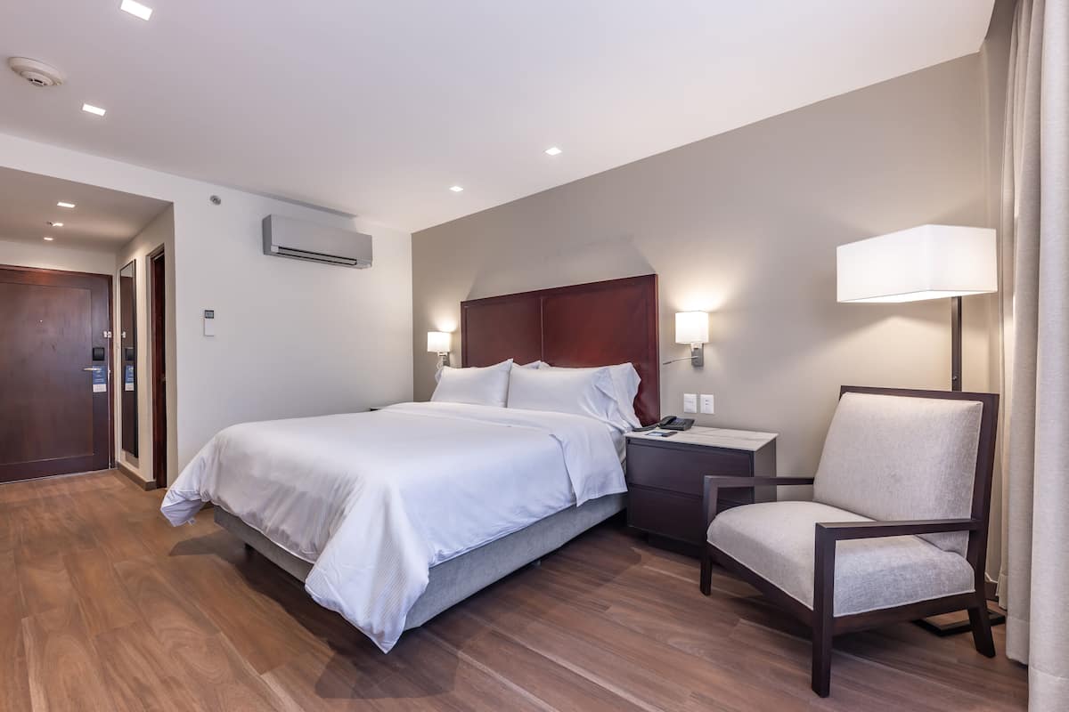 Une chambre d’hôtel avec un grand lit, une table de chevet, une chaise et un bureau.