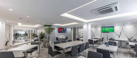 A modern conference room with marble flooring, black chairs, and tables, equipped with ceiling lights and air conditioning.
