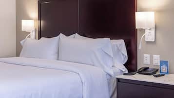 Una camera d'albergo con un letto grande, due lampade sui comodini, un telefono e un codice QR apposto sul tavolino.