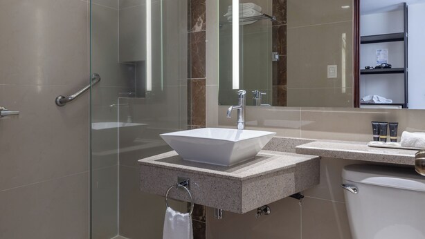 Ein modernes Badezimmer mit einer gläsernen Duschkabine, einem weißen Waschbecken und einer Toilette.