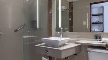 A modern bathroom with a glass-enclosed shower, a white sink, and a toilet.