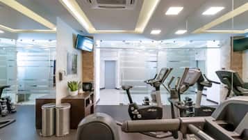 Une salle de sport moderne équipée de matériel d’exercice, d’un téléviseur et dotée de murs en verre.