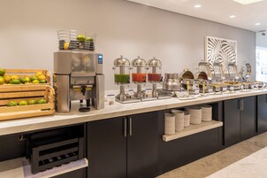 Ein reichhaltiges Buffet mit Kaffeemaschine, Saftspendern und einer Obstauslage.
