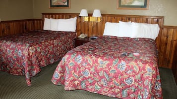 A hotel room with two beds, each with a floral bedspread and white pillows. There are two wall-mounted lamps and a telephone on a nightstand.
