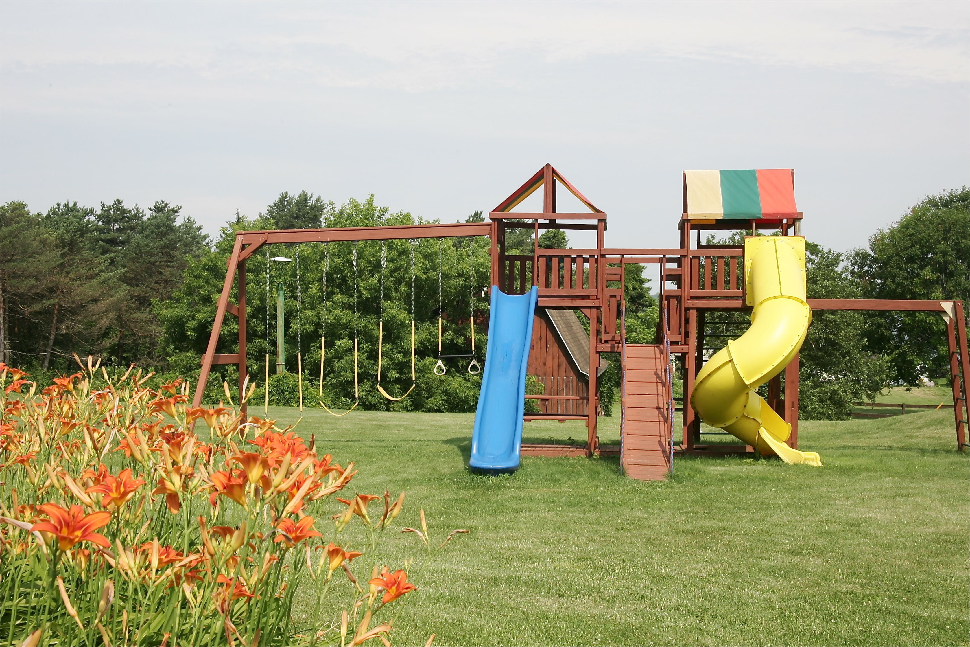 A playground with a wooden structure, a blue slide, and a yellow slide.