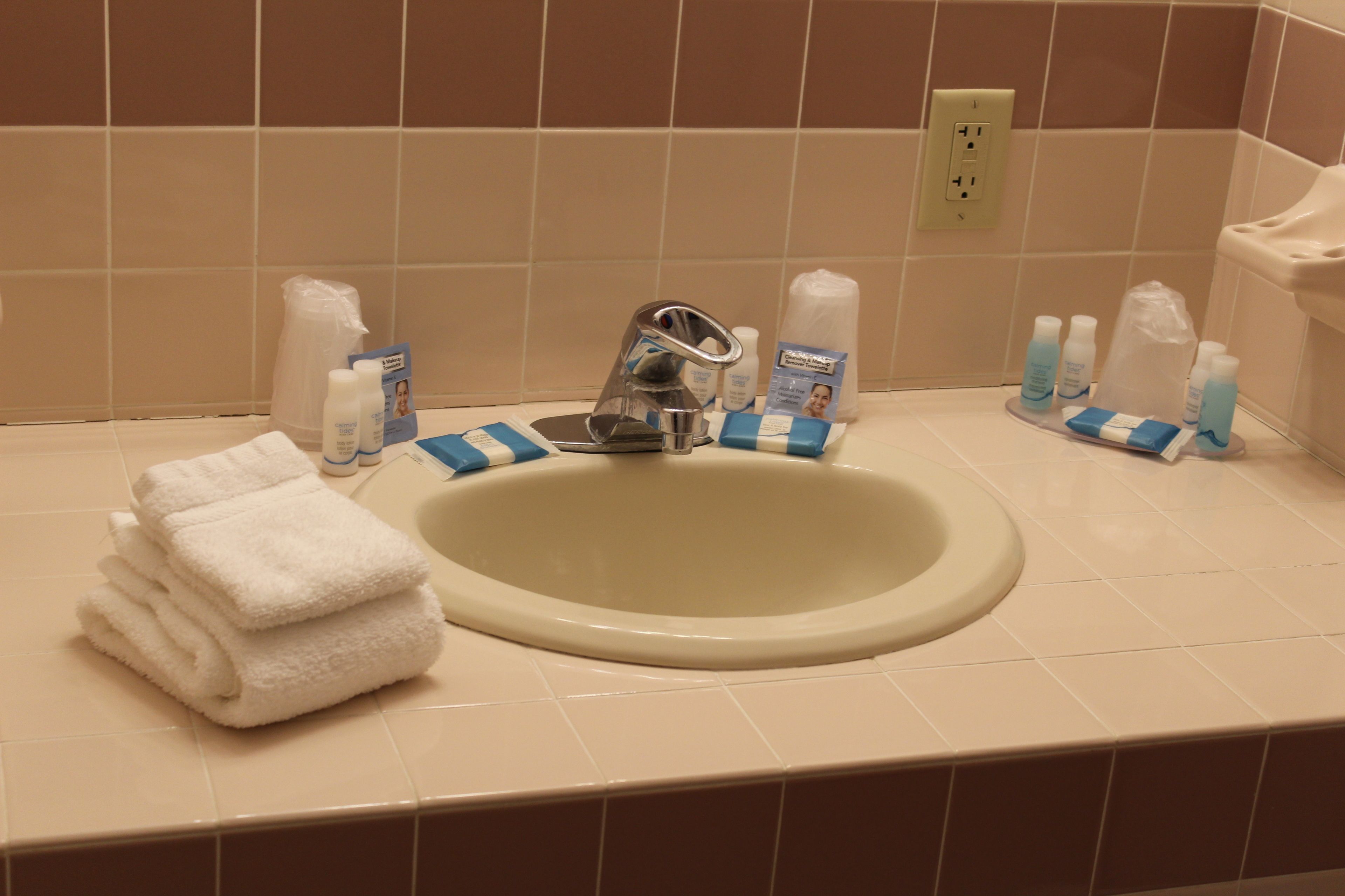 A bathroom sink with toiletries, a towel, and a soap dispenser.