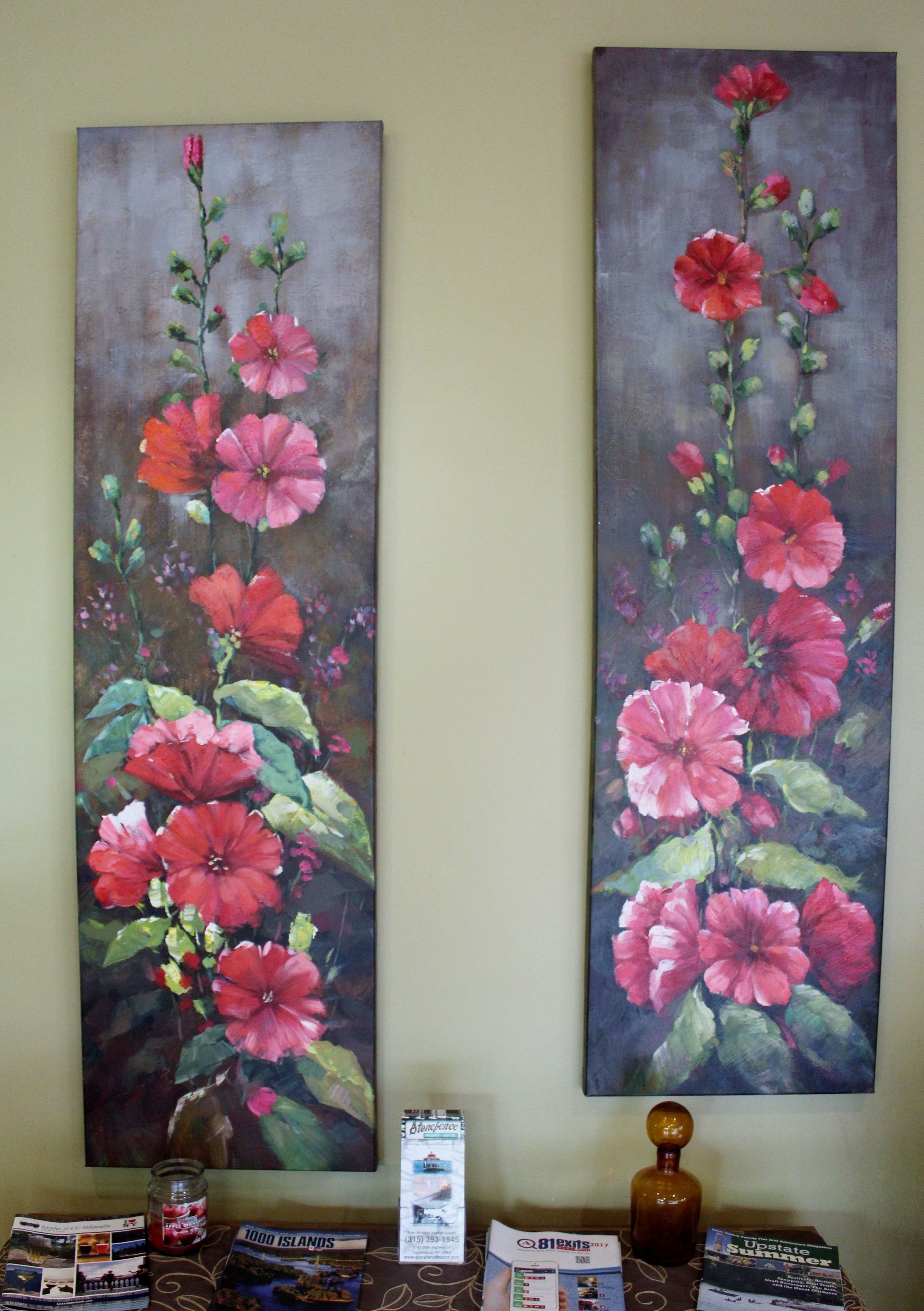 Two vertical paintings of red flowers on a wall.