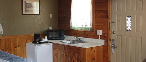 Una cocina compacta con armarios de madera, microondas y lavamanos.