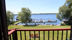 A lakeside view from a balcony with a red railing, docked boats, and a gazebo. - The Stonefence Resort (Ogdensburg)