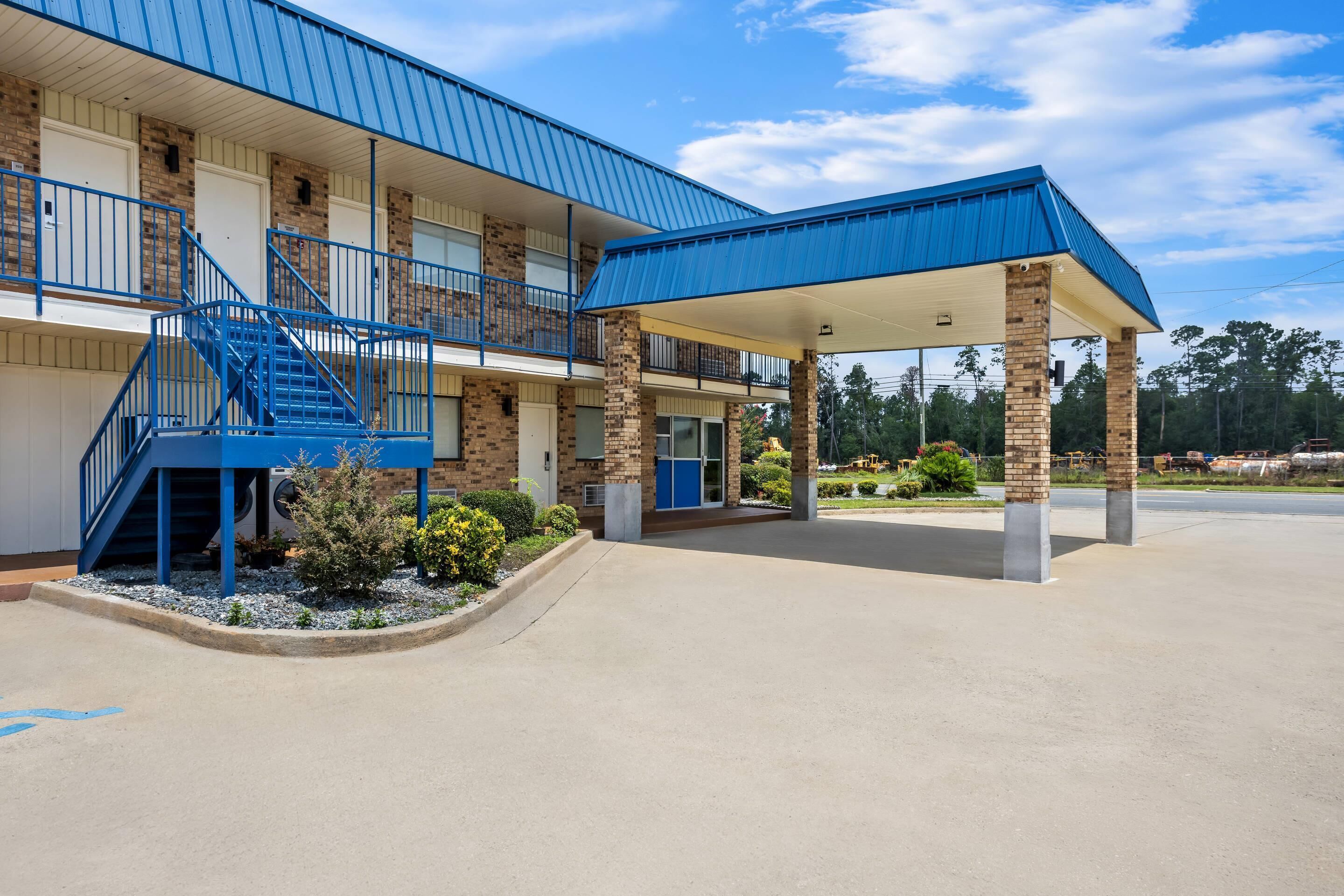 A two-story building with a covered parking area and a blue staircase.