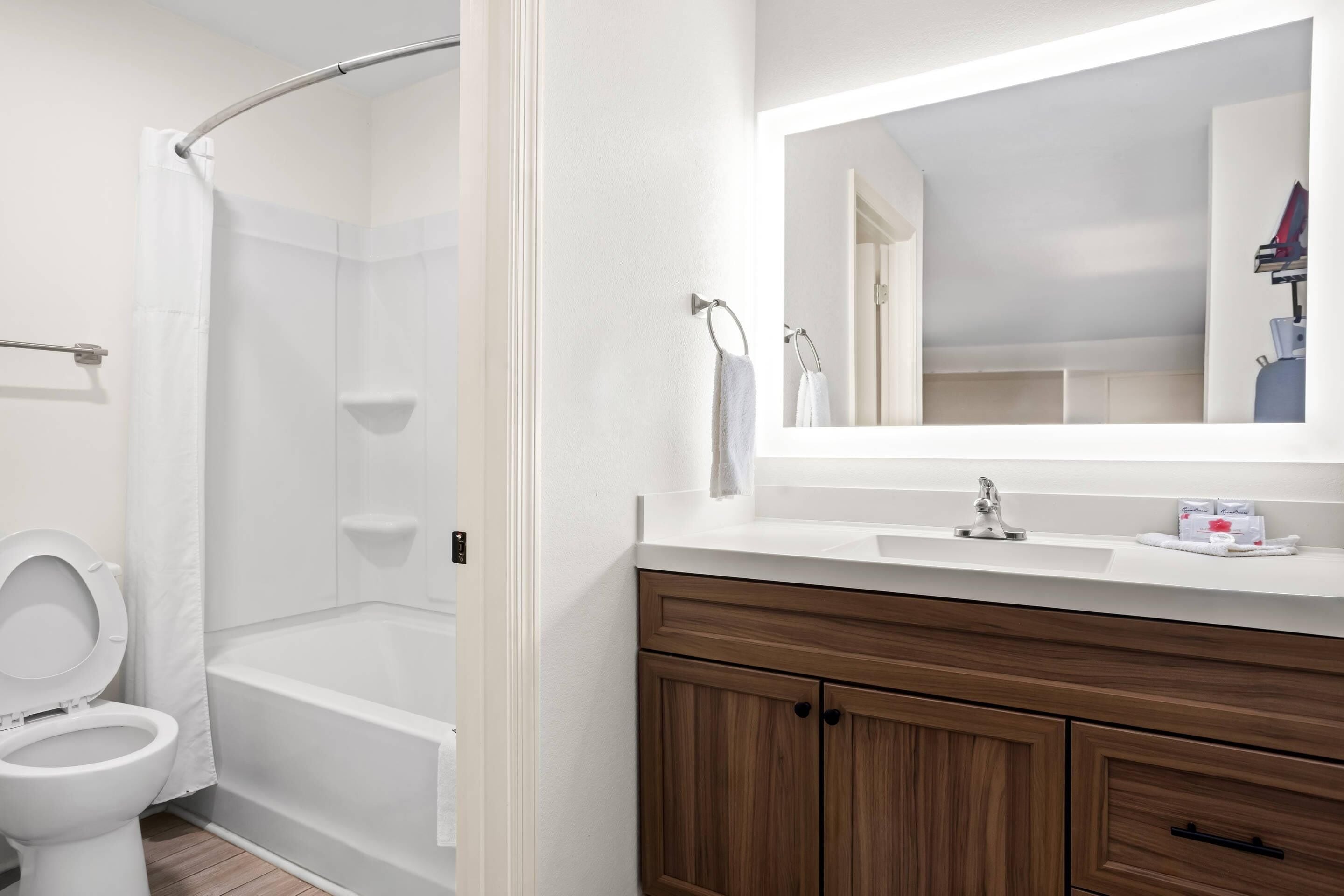 A bathroom with a toilet, a shower, and a vanity with a mirror.