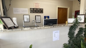A reception desk with a pet policy sign, a credit sign, and a snack bar sign. - Rodeway Inn Baxley (Baxley)