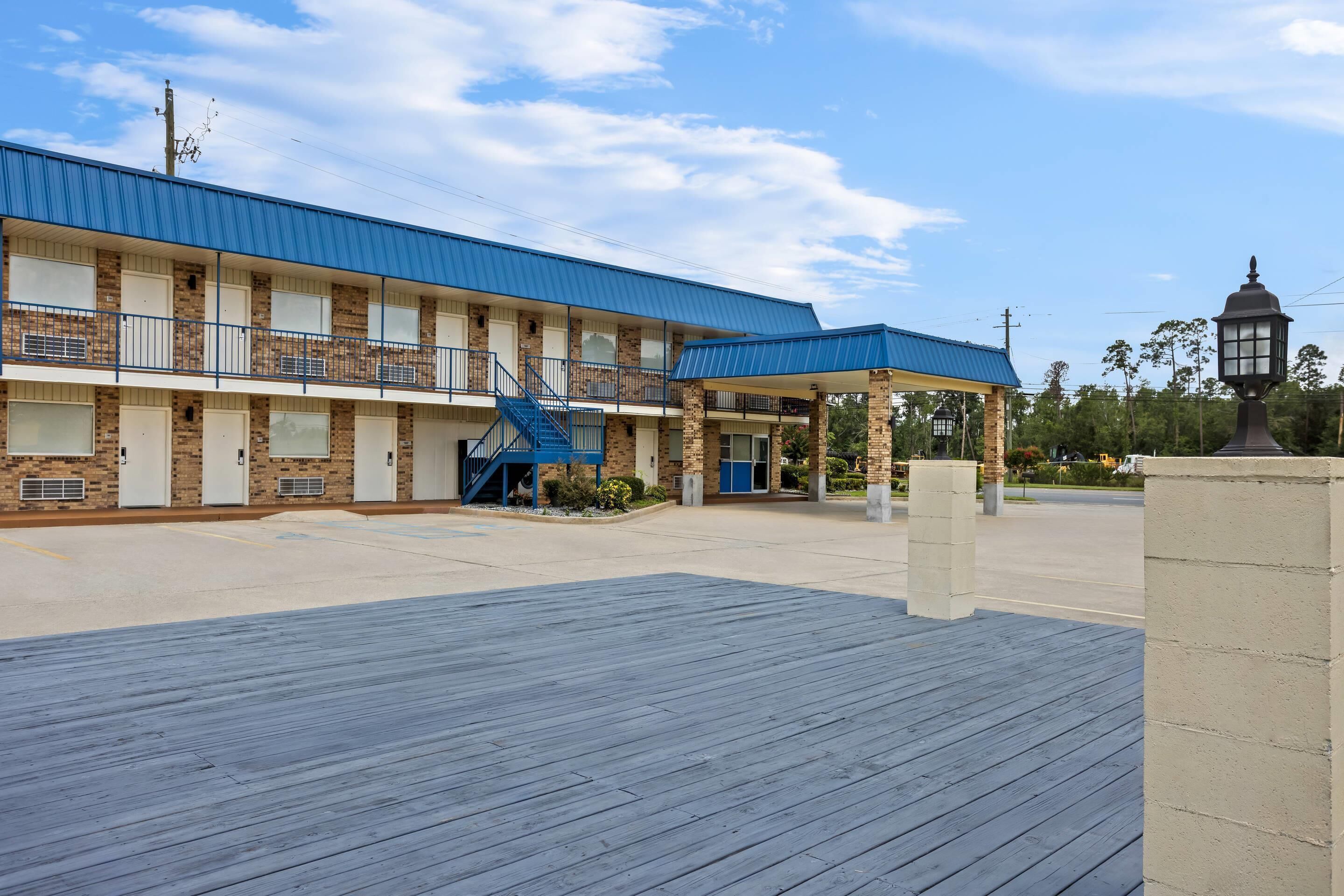 Ein Motel mit überdachtem Parkplatz und einer blauen Treppe zum Eingang.