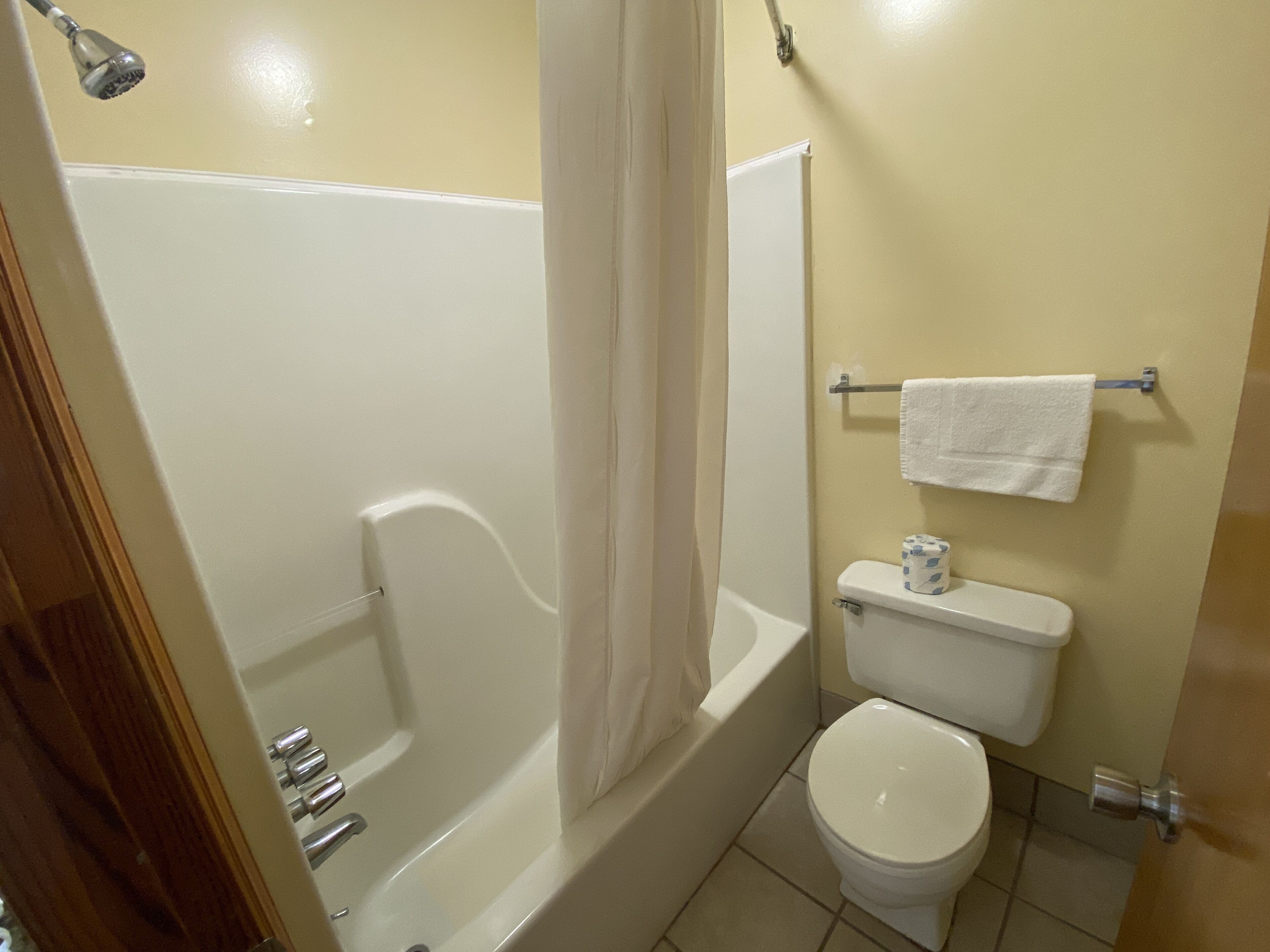 A bathroom with a bathtub, toilet, and a towel rack.