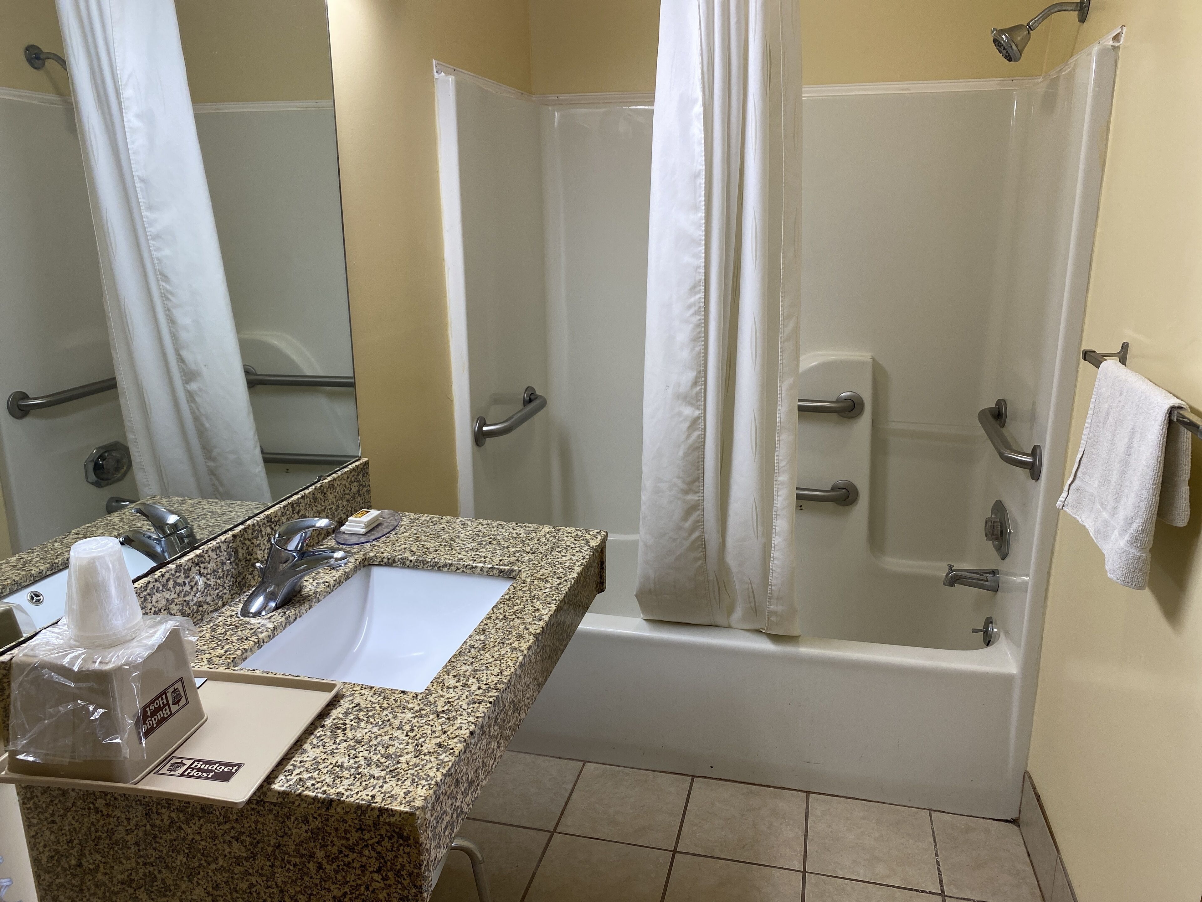A bathroom with a sink, mirror, shower, and bathtub.