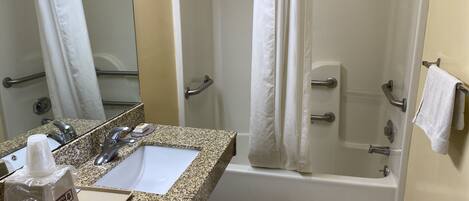 A bathroom with a sink, mirror, shower, and bathtub.