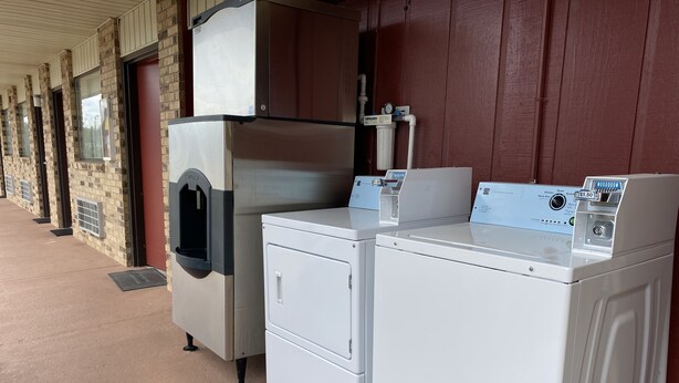 A laundry facility with a large industrial washer and dryer, a water fountain, and a control panel with a price display. - Rodeway Inn Baxley (Baxley)