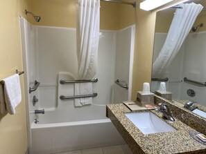 Une salle de bain avec une baignoire, une douche, un lavabo et un miroir.