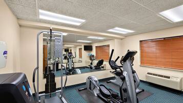 A gym with cardio machines, a weight machine, and a mirrored wall.