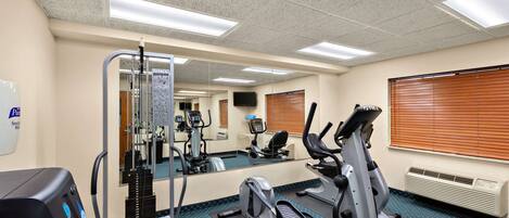 A gym with cardio machines, a weight machine, and a mirrored wall.